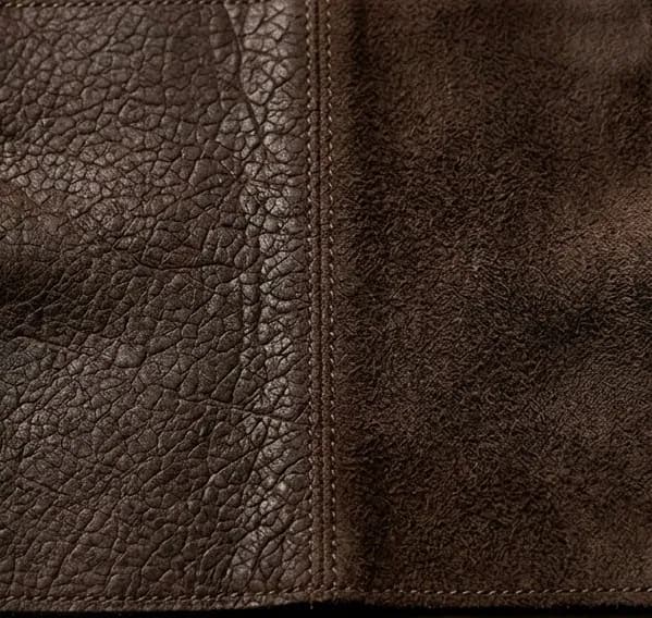Macro shot of brown crackle-textured sheepskin leather showing distressed outer surface and soft suede backing